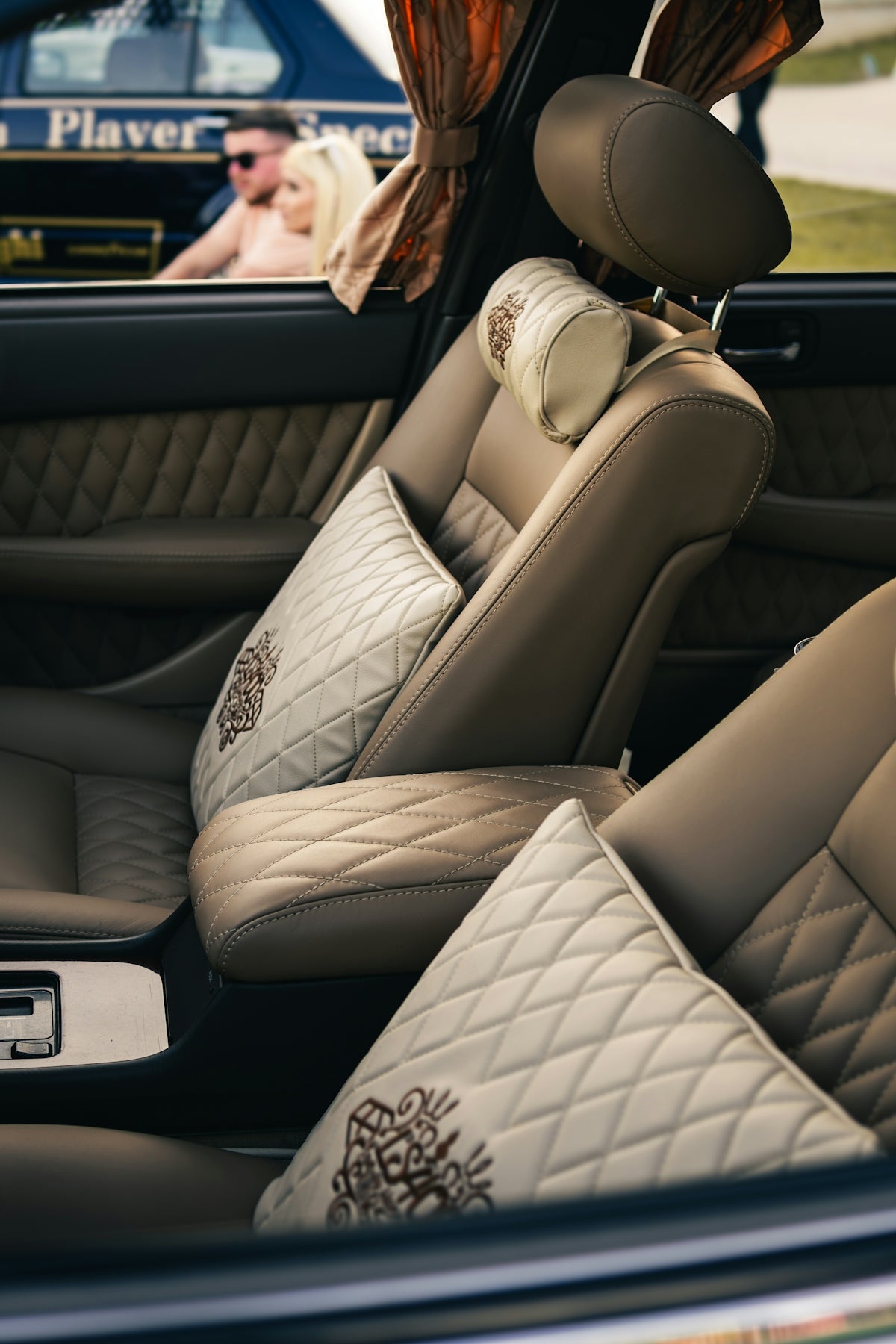 Luxury car interior with plush seats and pillows.