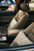 Luxury car interior with plush seats and pillows.